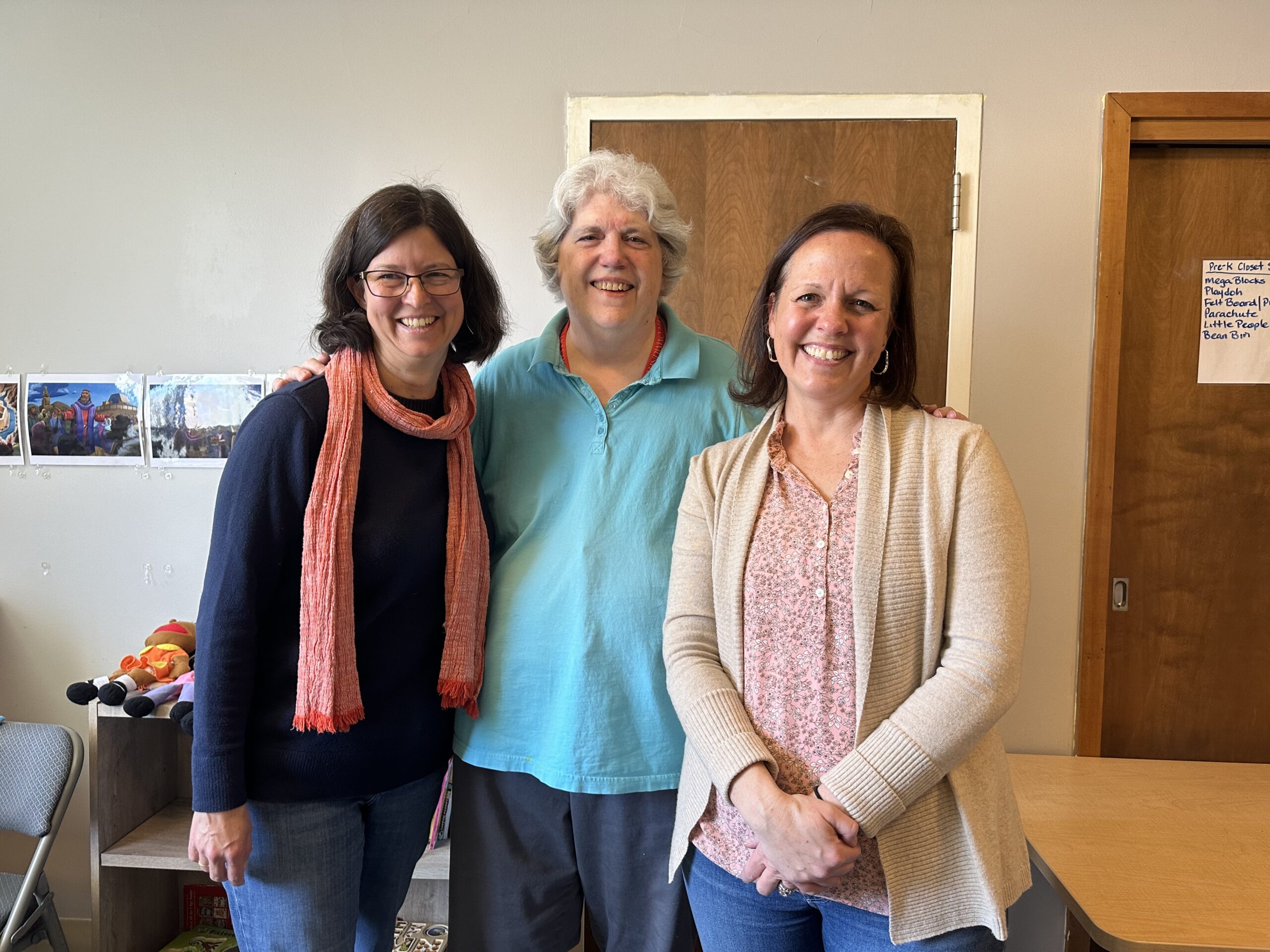 A group of three GROW teachers standing next to each other and smiling