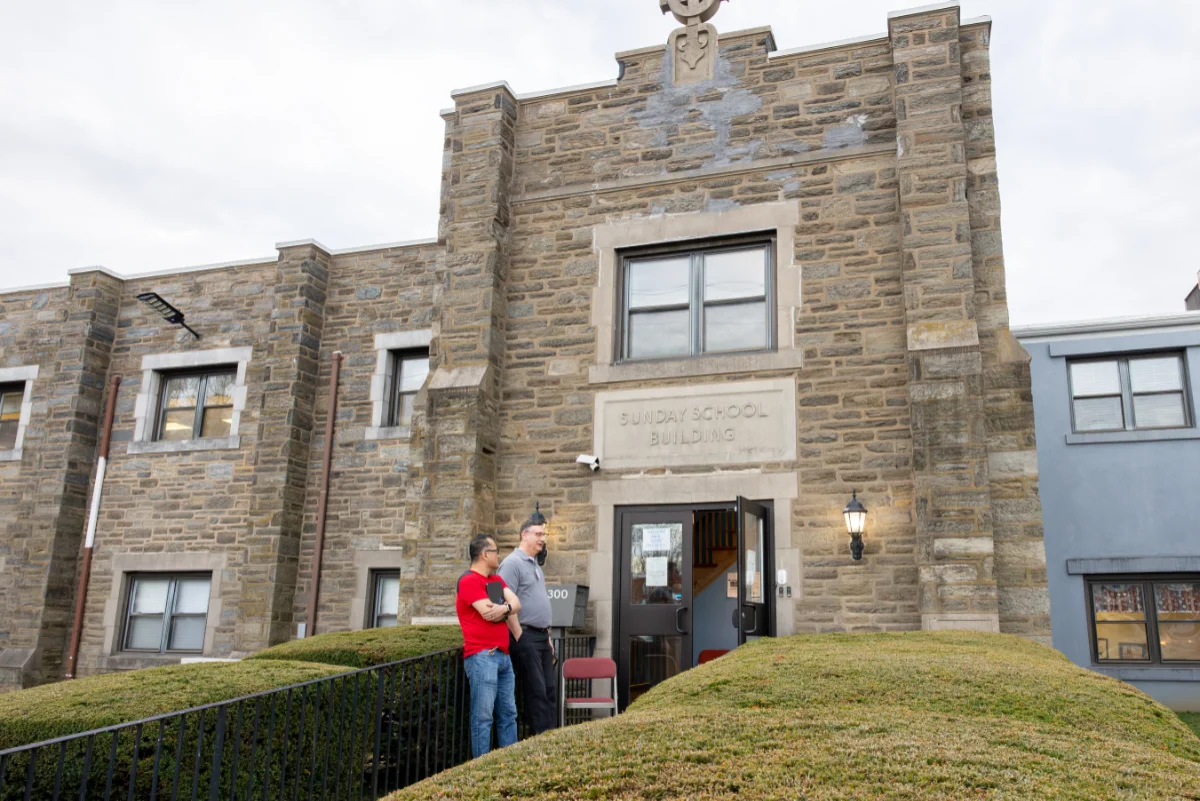Two men talking in front of a church building