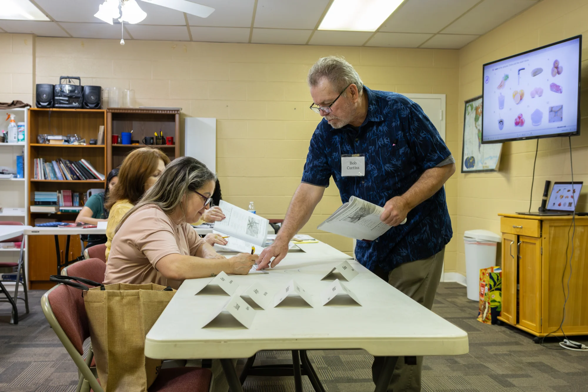 A GROW teacher helping a student with her worksheet during class.